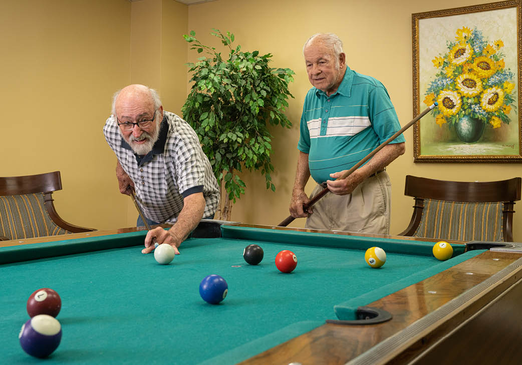 Residents enjoy a game of pool in the billiards room.